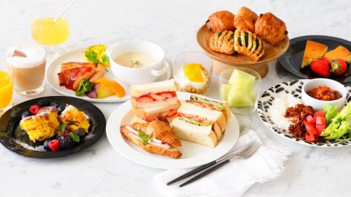 a table with plates of breakfast foods and drinks at Candeo Hotels Kobe Tor Road in Kobe