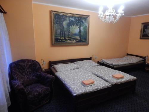 a bedroom with a bed and a chair and a chandelier at Penzion Dřevěnka in Osečná