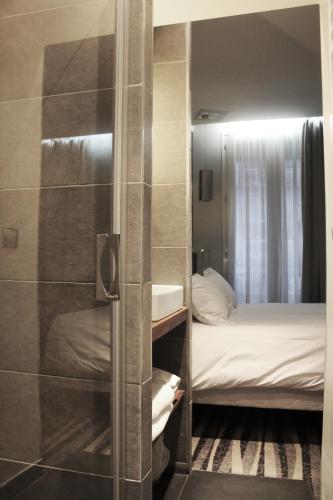 Cette chambre comprend un lit et une salle de bains pourvue d'une douche. dans l'établissement Hôtel Lumières Montmartre Paris, à Paris