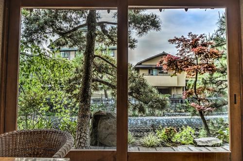 a window view of a garden outside a house at K's House Ito Onsen - Historical Ryokan Hostel in Ito