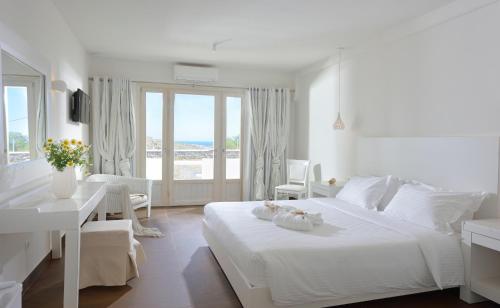a white bedroom with a large white bed and a table at Jenny's Summer Houses in Platis Yialos Mykonos