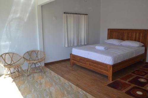 a bedroom with a bed and two chairs at Kondo Villa in Labuhan Pandan