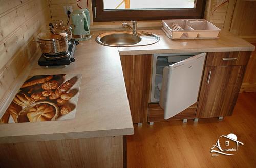 a kitchen with a sink and a counter with food on it at AMANDA Domki letniskowe in Darłowo