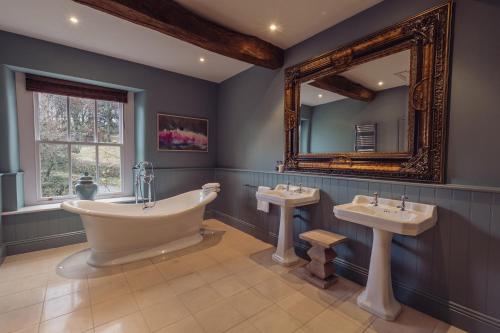 a bathroom with a tub and two sinks and a mirror at Plough Inn in Lupton