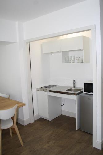 a white kitchen with a sink and a table at Hôtel de la Rhune in Ascain
