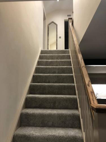 a staircase in a building with grey carpeted stairs at Camerton Inn Cottage in Bath