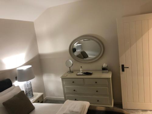 Dormitorio con cama con espejo y tocador en Camerton Inn Cottage, en Bath