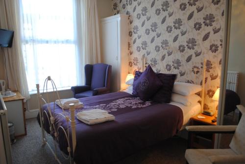 a bedroom with a bed and a chair and a window at Craig-Ard Hotel in Llandudno