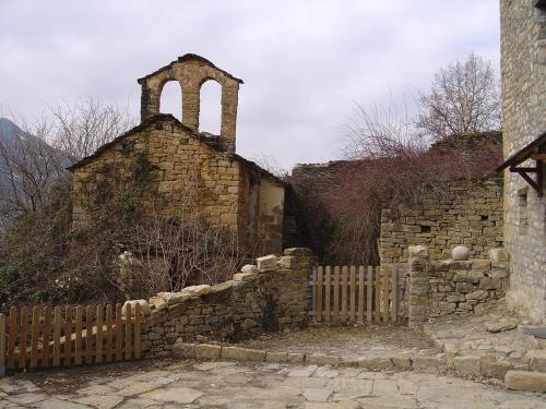 stary kamienny budynek z ogrodzeniem i kościołem w obiekcie Casa Rural Tomaso II w mieście Reperos