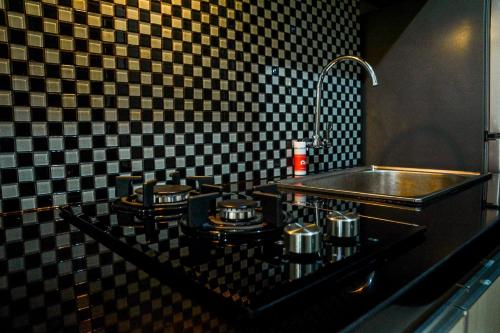 a kitchen with a sink and a counter with pots and pans at Minimalist Studio Room at Grand Serpong Apartment By Travelio in Tangerang