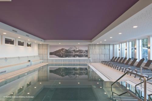 a large swimming pool with chairs and a swimming pool at Hapimag Ferienwohnungen Sonnleitn in Sonnenalpe Nassfeld