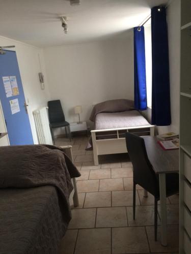 a bedroom with a bed and a desk and a table at Les Callunes anciennement Le Beauséjour in Annot