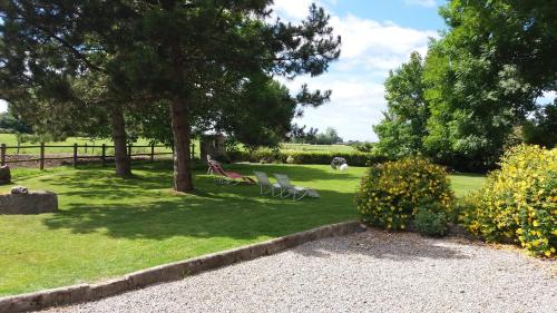 a park with two chairs and trees and grass at Manoir de la Ville Marie in Hirel
