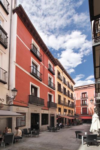 a red building with tables and chairs in a courtyard at Apartamentos El Tiempo in Madrid