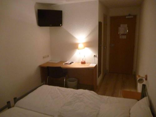 a bedroom with a bed and a desk with a lamp at Hotel Primo Colmar Centre in Colmar