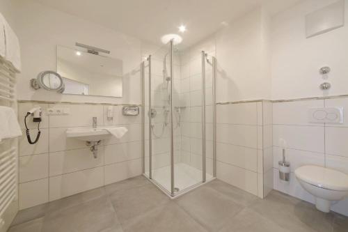 La salle de bains est pourvue d'une douche, d'un lavabo et de toilettes. dans l'établissement Hotel ChiemseePanorama, à Gstadt am Chiemsee