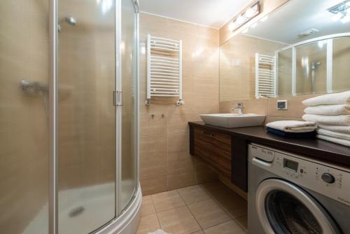 a bathroom with a shower and a washing machine at Apartamenty Apartinfo Na Klifie in Władysławowo