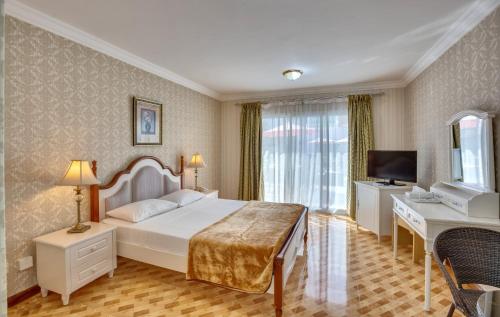 a bedroom with a bed and a desk and a television at Al Khalidiah Resort in Sharjah