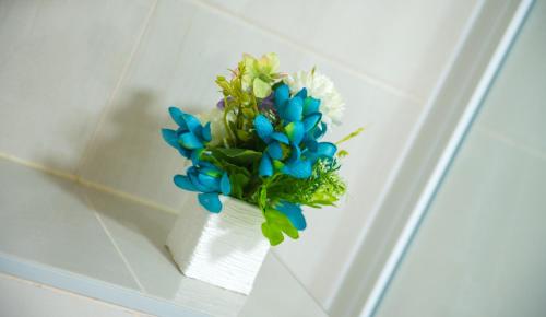 a white vase with blue and white flowers in it at Five Rivers Rooms in Mostar