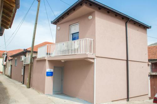 a pink building with a balcony on a street at Five Rivers Rooms in Mostar
