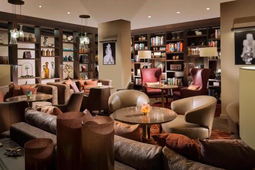 a library with couches and tables and bookshelves at Acasa Suites Zurich Oerlikon in Zürich