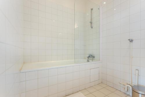 La salle de bains est pourvue de carrelage blanc, d'une baignoire et d'un lavabo. dans l'établissement Cosy studio 4P Trocadero-Eiffel Tower, à Paris