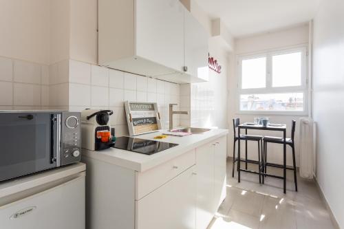 - une cuisine blanche avec un four micro-ondes et une table dans l'établissement Cosy studio 4P Trocadero-Eiffel Tower, à Paris