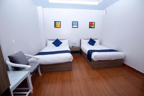 a small room with two beds and a chair at Catba Central Hotel 2 in Cat Ba