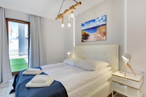 a white bedroom with a bed and a window at Apartinfo Aura Island in Gdańsk