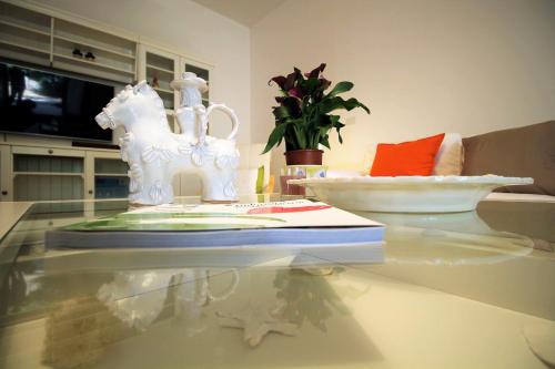 einen Glastisch mit einem Buch und einer weißen Pferdestatue darauf in der Unterkunft A casa di Emy by Holiday World in Pulsano
