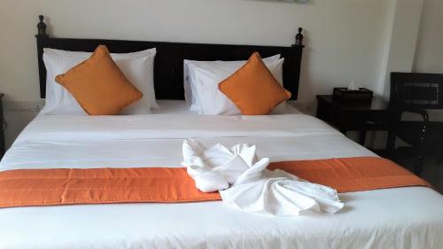 a white bed with orange and white sheets and pillows at The Pleasure Kosgoda in Bentota