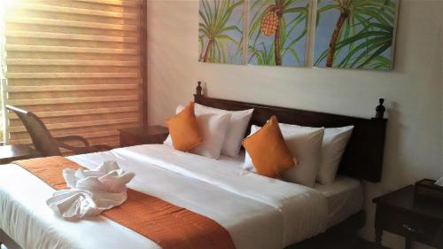a bedroom with a large bed with orange and white pillows at The Pleasure Kosgoda in Bentota