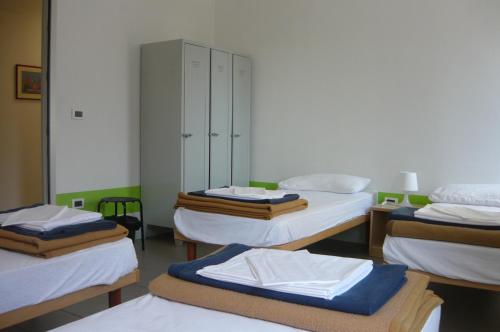 アクイレイアにあるOstello Domus Augusta Aquileiaのベッド4台とキャビネットが備わる客室です。
