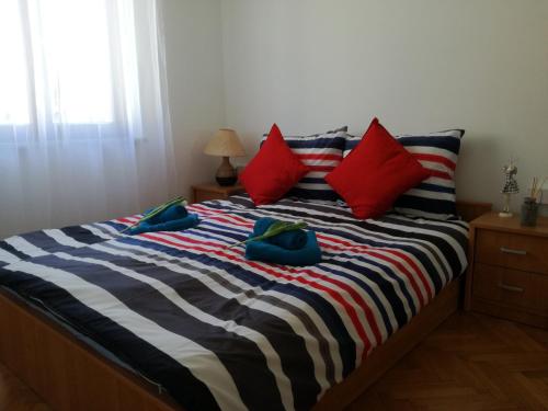 a bed with red and blue pillows on it at Apartman Una in Crikvenica
