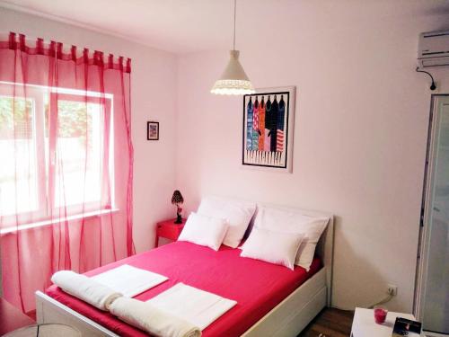 ein Schlafzimmer mit einem rosa Bett und einem Fenster in der Unterkunft Violet Red Yellow Apartments in Korčula