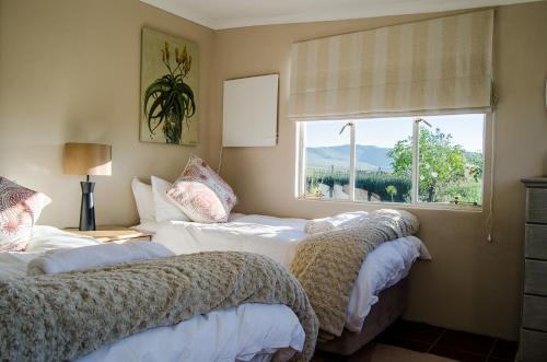 deux lits dans une chambre avec une fenêtre dans l'établissement Milky Lane Cottage, à Mooirivier