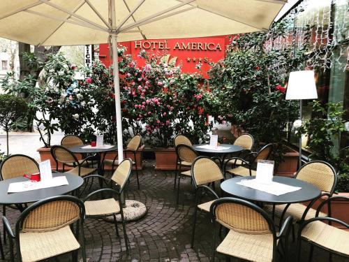 an outdoor cafe with tables and chairs and flowers at Hotel America in Trento