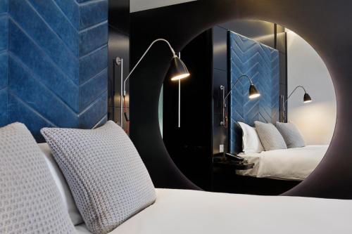 ロンドンにあるザ ホクストン ショーディッチのベッド2台と鏡が備わる客室です。