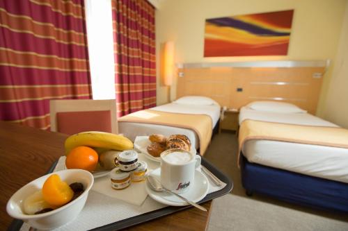 a hotel room with two beds and a tray of food at UNA HOTELS Cesena Nord in Cesena
