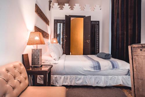 a bedroom with two beds and a lamp and a chair at Ambre Epices Medina Riad in Marrakech