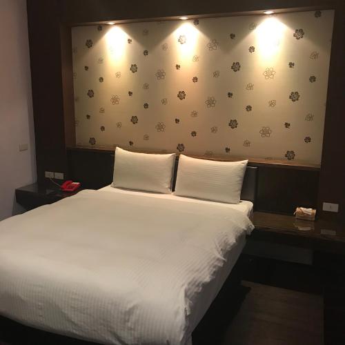a bedroom with a white bed with two pillows at Baseball Hotel in Hsinchu City