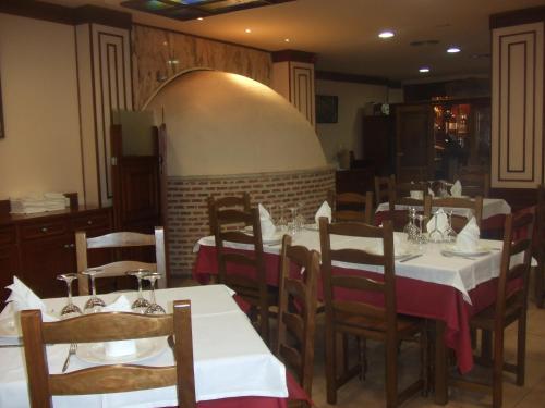 un comedor con mesas y sillas con manteles blancos en Hotel Vadorrey en Roa
