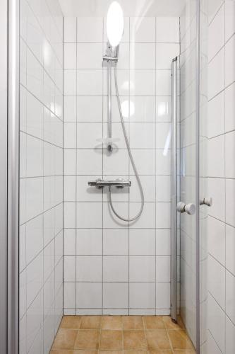 a shower in a white tiled bathroom at LS Apartments in Bergen
