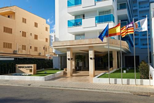 three flags flying in front of a building at Hipotels Hipocampo - Adults Only in Cala Millor
