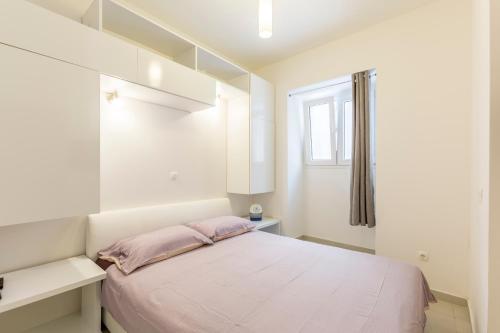 a white bedroom with a bed and a window at Apartment DeLux in Split