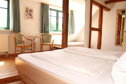 a bedroom with a bed and a table and chairs at Landgasthof "Wirtshaus Zur Eibe" in Jabel