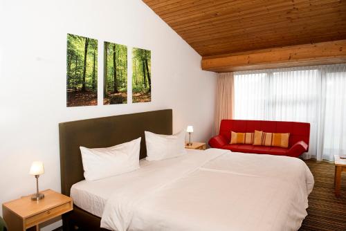 a bedroom with a large bed and a red chair at Akzent Hotel Höhenblick in Mühlhausen im Täle