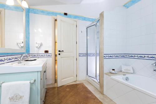 a bathroom with a tub and a sink and a bath tub at Hotel Poseidonia in Àrbatax