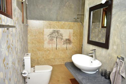 a bathroom with a white toilet and a sink at Thambili Cabanas in Hikkaduwa