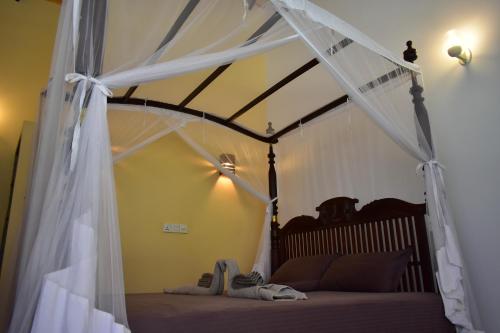 a bedroom with a canopy bed with shoes on it at Thambili Cabanas in Hikkaduwa